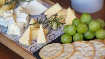 A charcuterie board with various cheeses, crackers, and grapes on a wooden board.