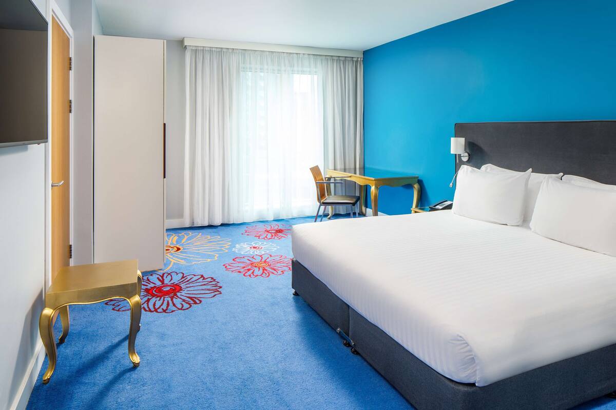A hotel room with a large bed, a desk, and a chair.