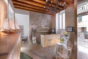 A cozy kitchen with a wooden ceiling, a bar area, and a dining space with white chairs and a table.