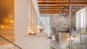 A hotel interior with a staircase, a chandelier, a ship model, and a dining area with chairs and a table. - Hotel Marco Polo (Verona)