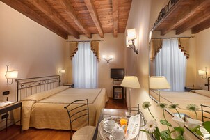 A hotel room with two beds, a television, a table with breakfast items, and a mirror.