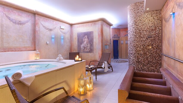 A spa area with a hot tub, seating, and a mosaic wall. - Hotel Marco Polo (Verona)