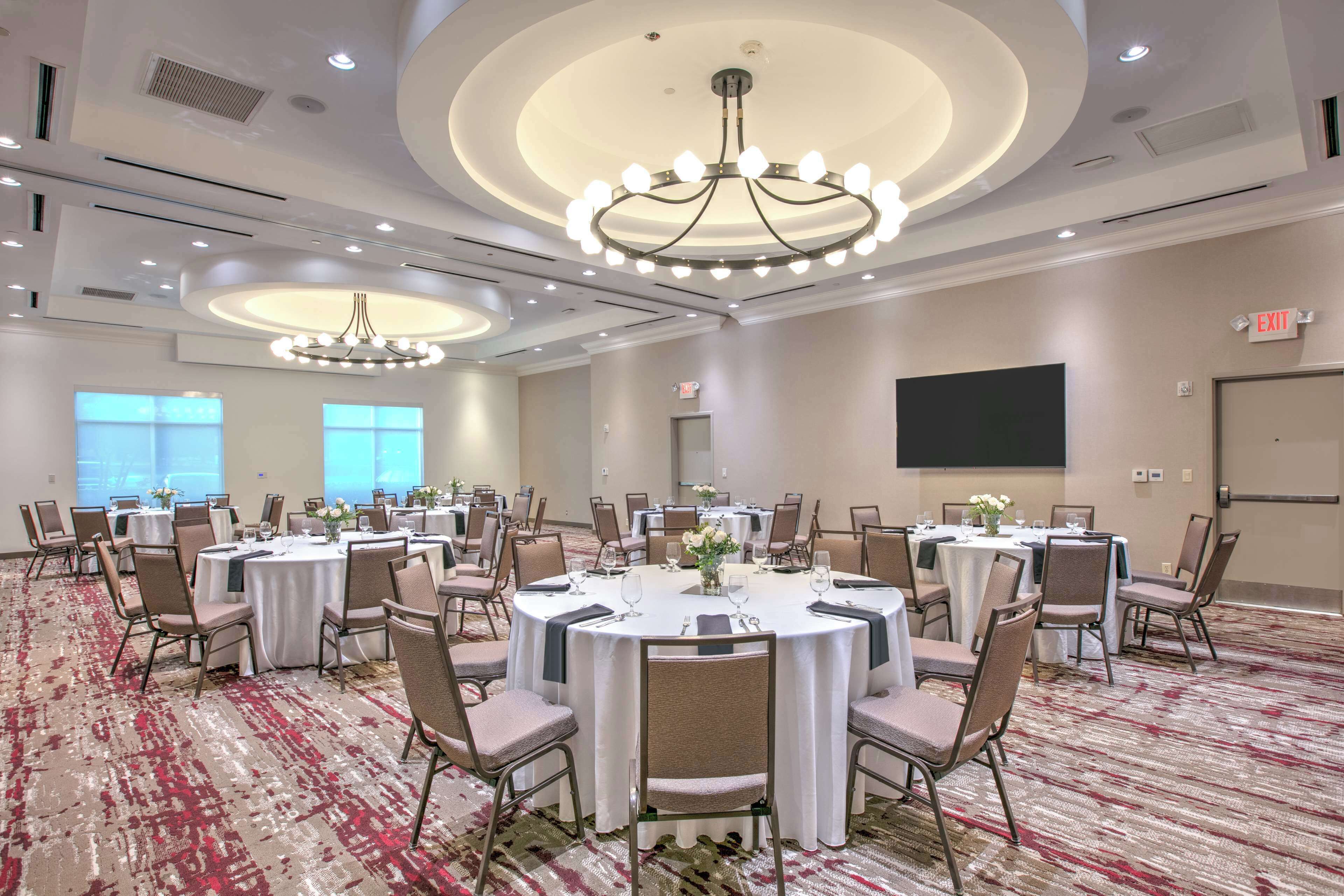 A conference room with round tables, chairs, and a large screen.