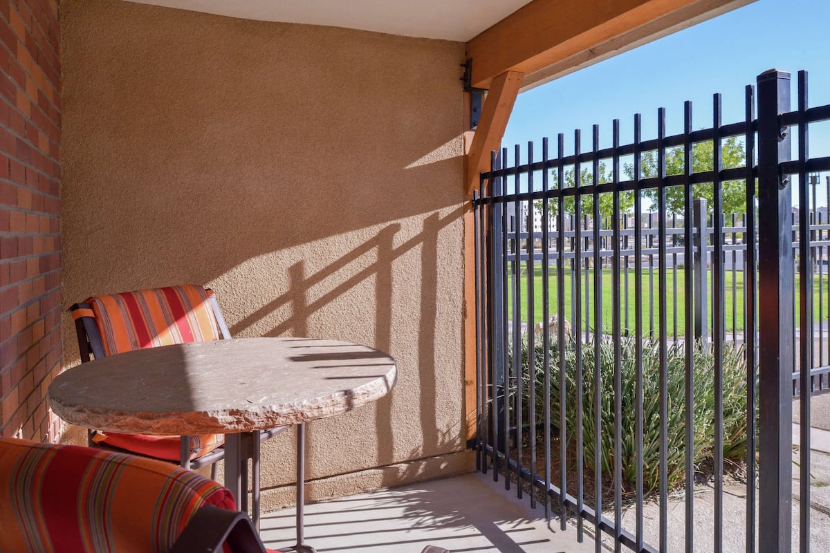 Un balcon avec une table et des chaises, une vue sur un cimetière et une clôture en métal noir.