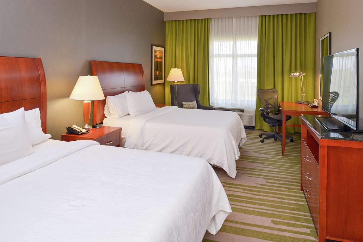 Une chambre d’hôtel avec deux lits, un bureau avec un ordinateur, une chaise, une lampe et un téléviseur.
