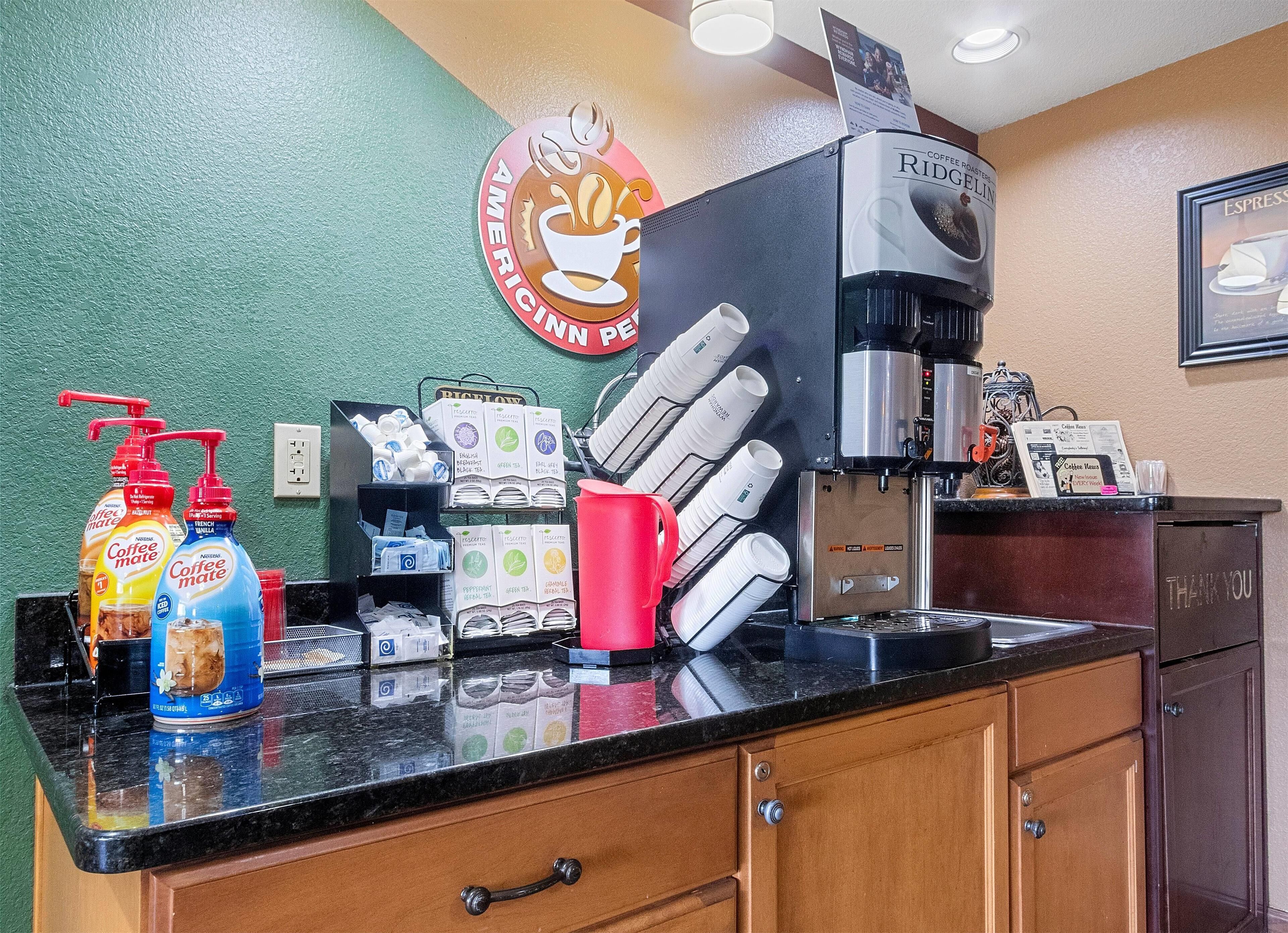 A coffee station with a coffee machine, disposable cups, and coffee pods.