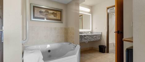 A modern bathroom with a large bathtub, a marble countertop, and a framed landscape painting on the wall.