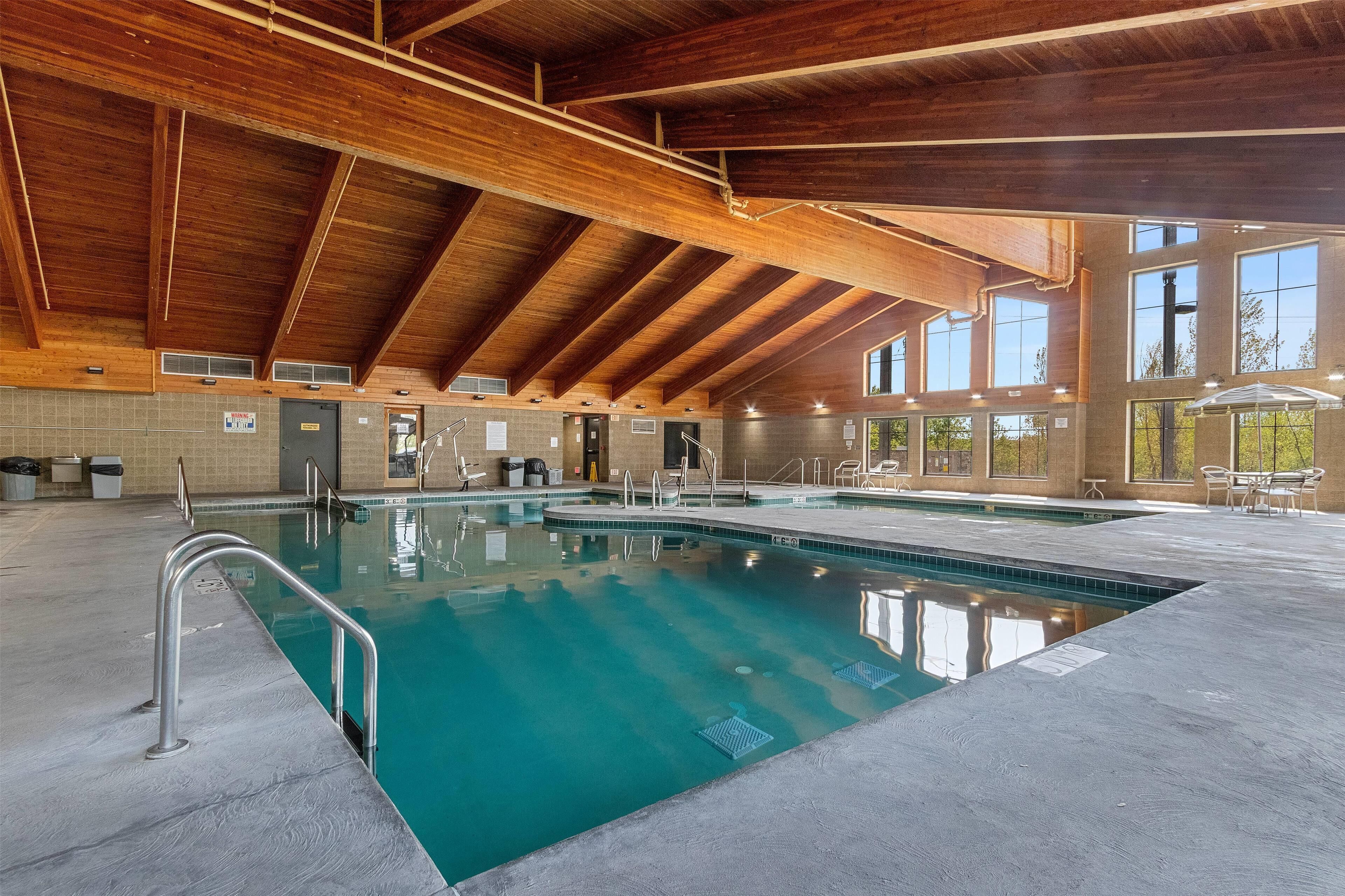 Una piscina interior con techo de madera y ventanas amplias.