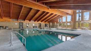 Una piscina interior con techo de madera y ventanas amplias.