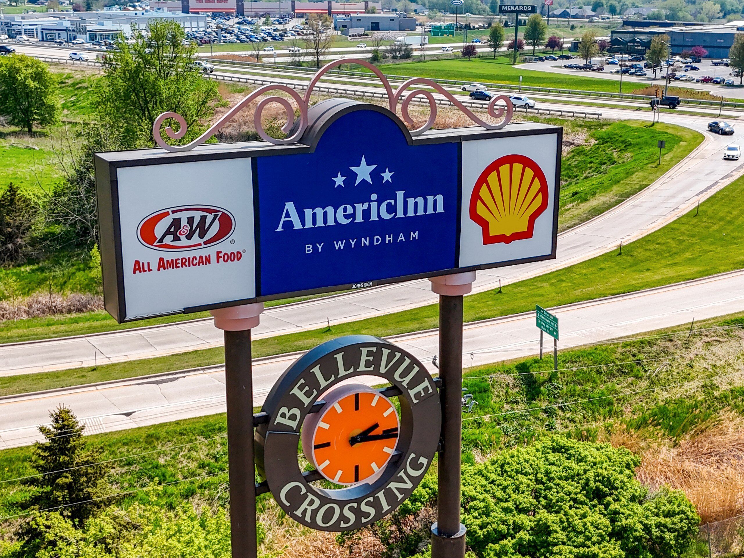 A signboard with logos of AmeriInn and Shell, and a clock indicating Bellvue Crossing.
