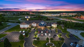 A hotel with a central parking lot, multiple buildings, and a surrounding landscape. - AmericInn by Wyndham Green Bay East (Green Bay)