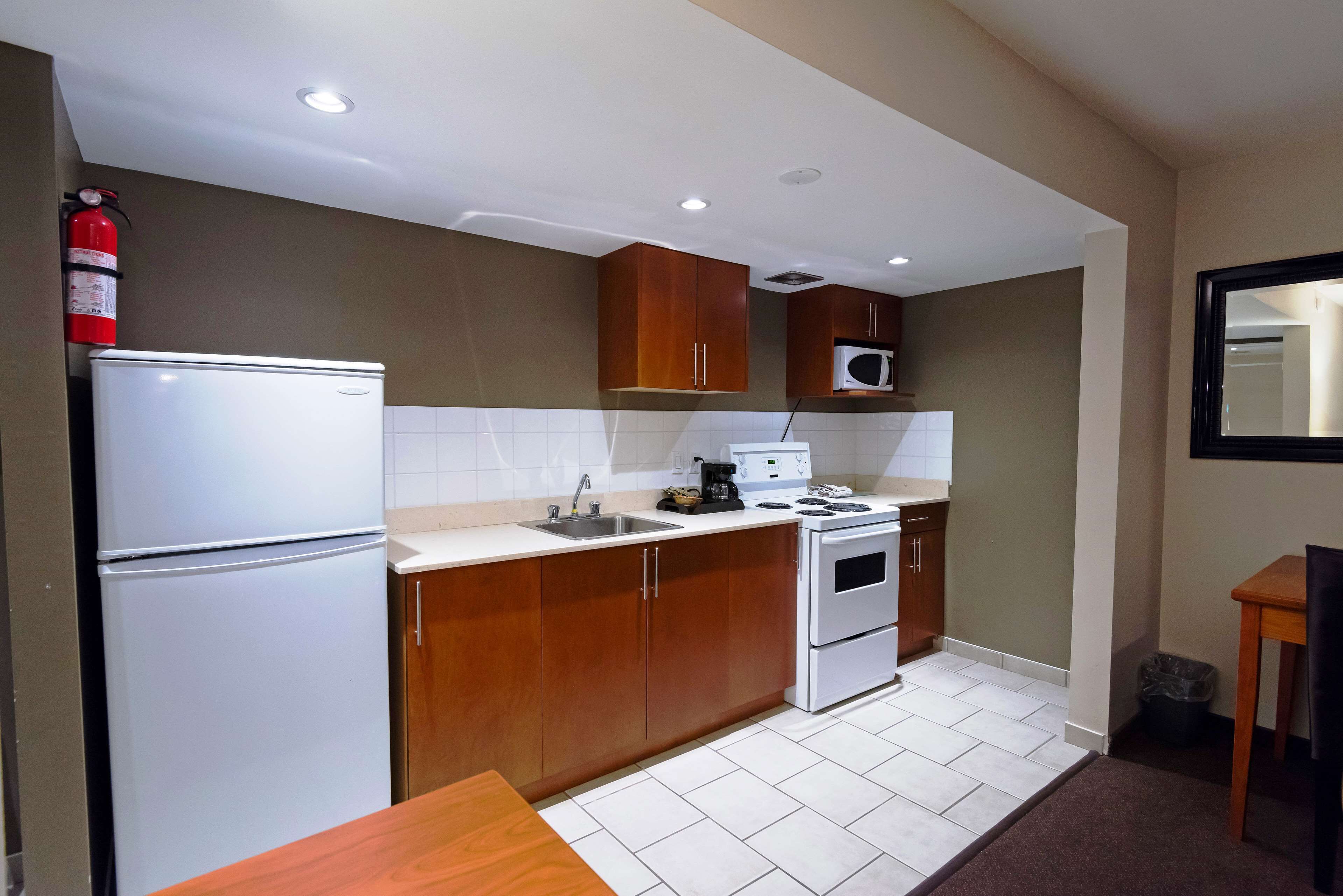 Una cocina compacta equipada con refrigerador, microondas, estufa y lavamanos.