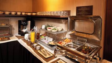 Montaje tipo bufé con diferentes alimentos, una máquina de café y un dispensador de bebidas.