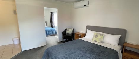 A bedroom with a bed, a nightstand, a chair, and a window.