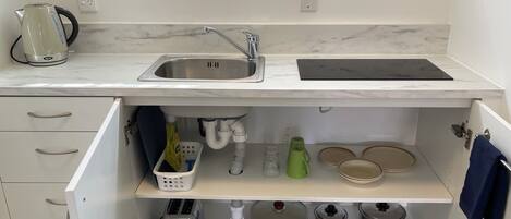 Una cocina compacta con un lavamanos, hervidor, tostadora y estufa.