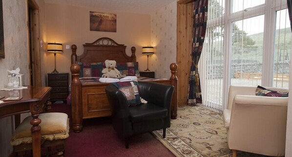 A bedroom with a bed, two bedside lamps, a chair, a desk, and a window with a view. - The Steadings at The Grouse & Trout (Inverness)