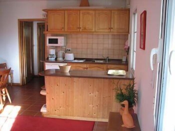 A kitchen with wooden cabinets, a microwave, and a sink. - Valle Paraizo (Santa Cruz)