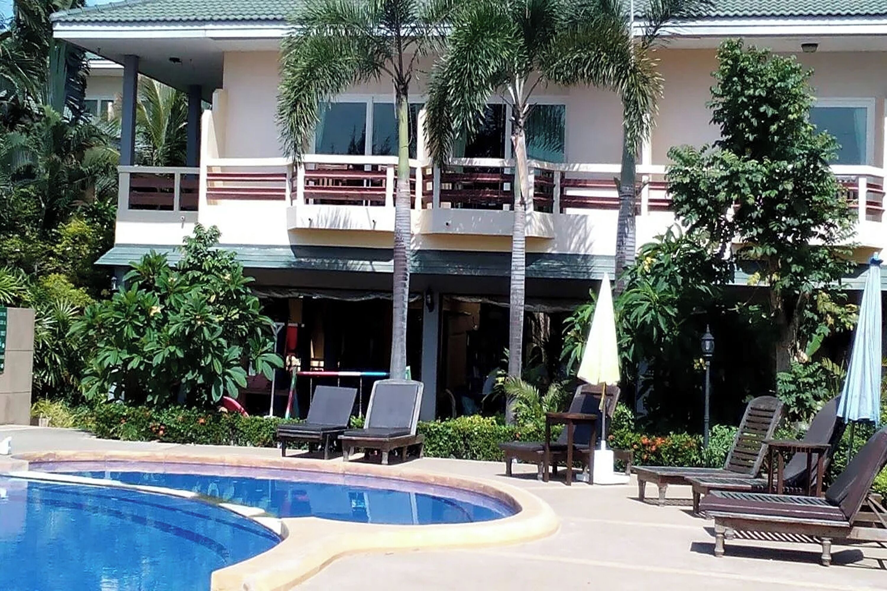A hotel with a pool area, lounge chairs, and a covered outdoor seating area.