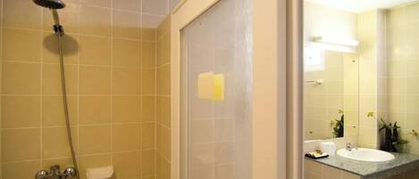 Un baño con ducha, inodoro, lavamanos y espejo.