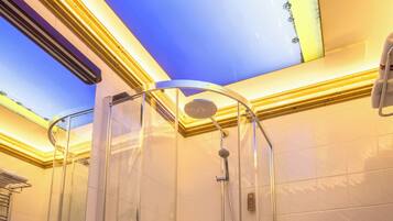 Un baño moderno con ducha envuelta en vidrio, tocador de madera y pared con azulejos blancos.