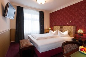 A hotel room with a large bed, a television mounted on the wall, a desk with a lamp, and a chair. - Myer's Hotel Berlin (Berlin)