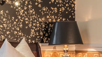 Ein Hotelzimmer mit einem Bett, einem Nachttisch, einer Lampe und einer Wand mit floralem Muster.