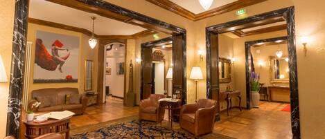 A spacious lobby with leather seating, a patterned carpet, and marble-framed mirrors.