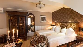Ein Hotelzimmer mit zwei Betten, einem großen Spiegel, einer Chandelier und einer Obstschale auf dem Nachttisch.