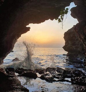 A natural rock formation with a cave entrance overlooking a body of water.