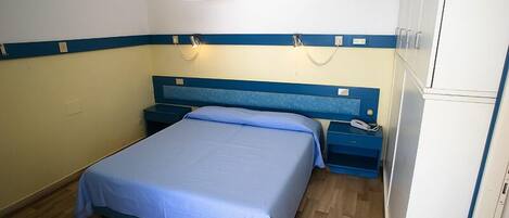 Un dormitorio con una cama individual, mesitas de noche, un teléfono y una lámpara de pared.