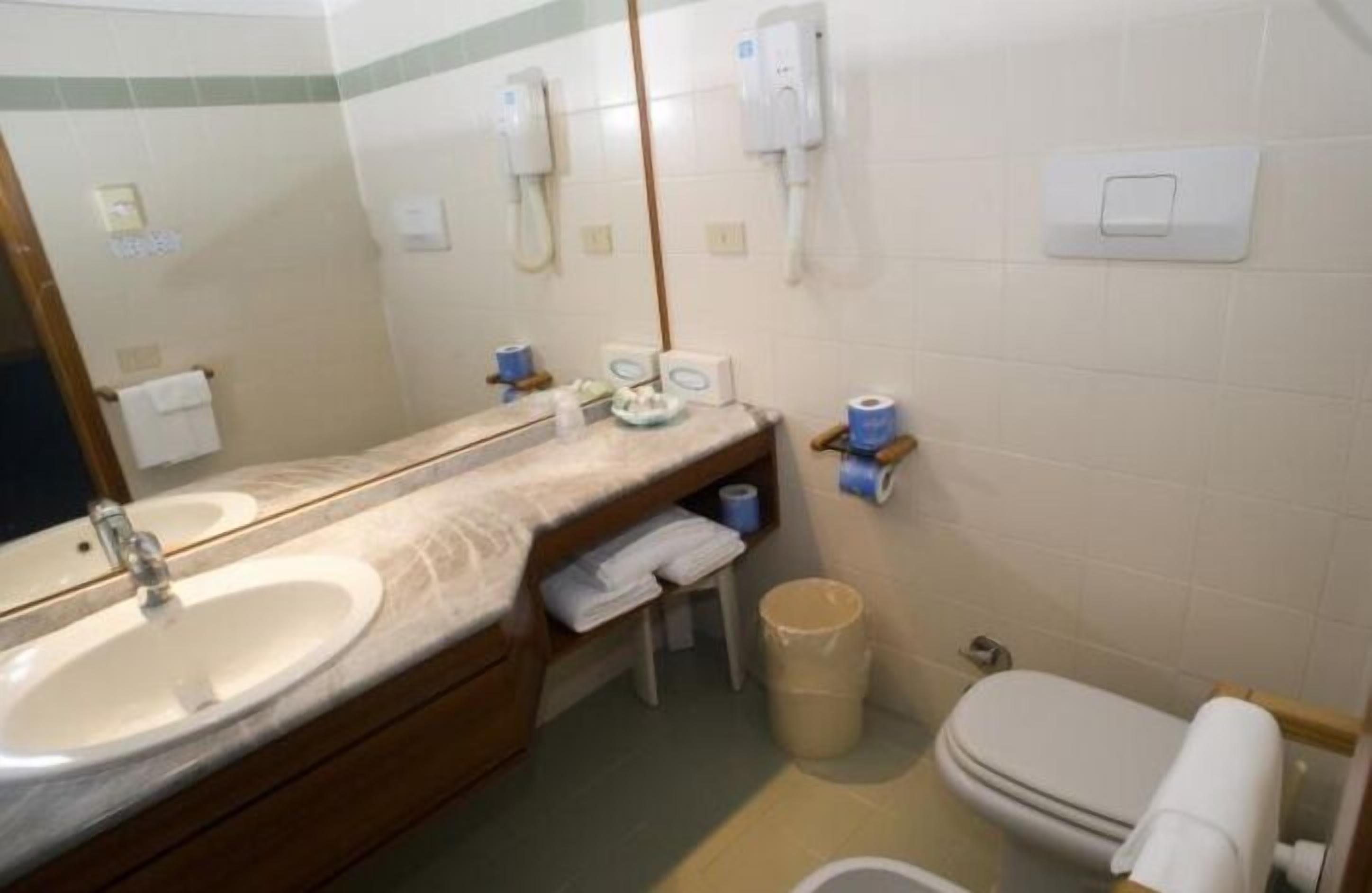 Ein Badezimmer mit Waschbecken, Spiegel, Toilette und Mülleimer.