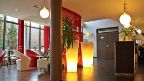 Eine moderne Lobby mit Empfangstresen, Sitzgelegenheiten und großen Fenstern.