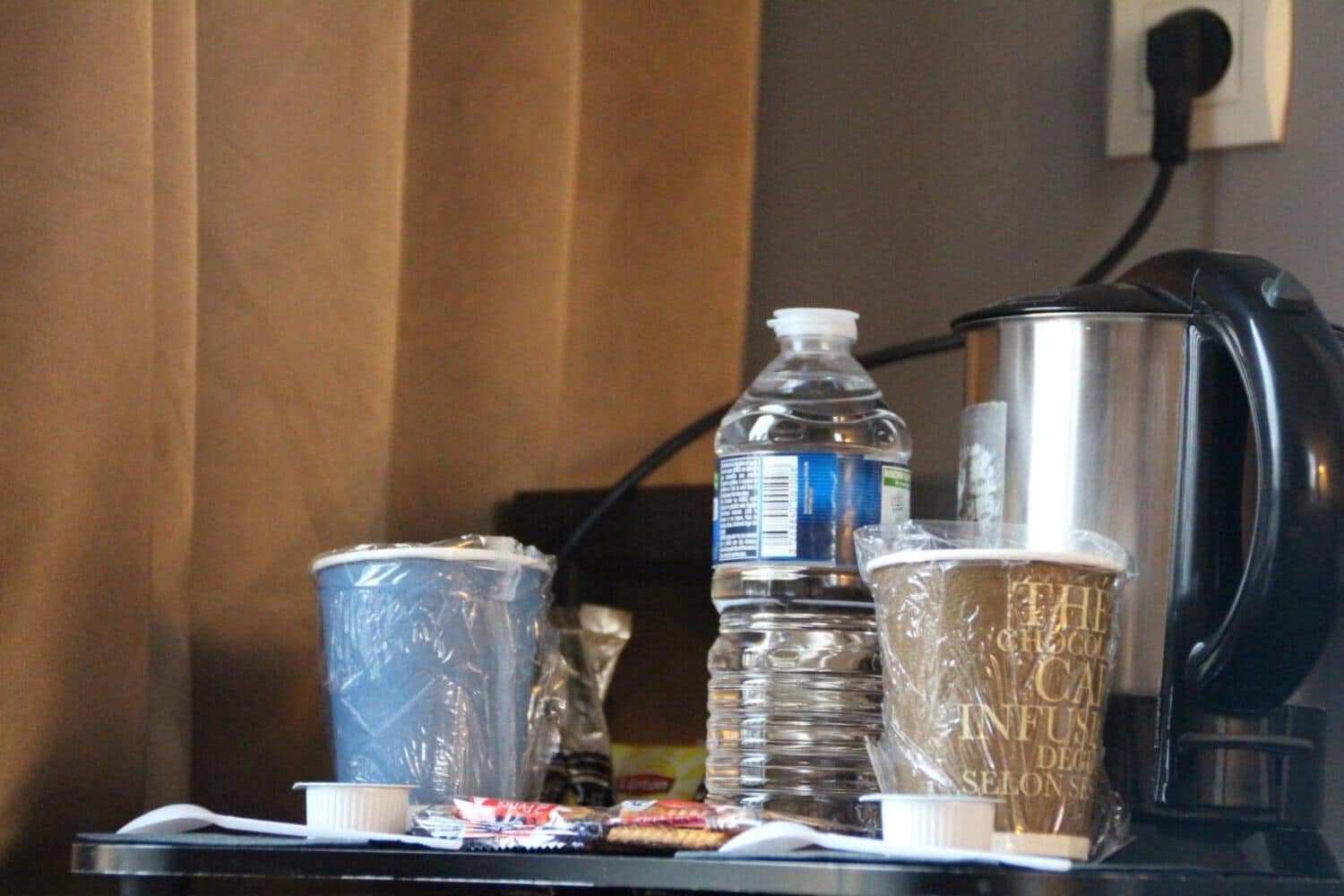 A table with a water bottle, a coffee maker, and two cups.