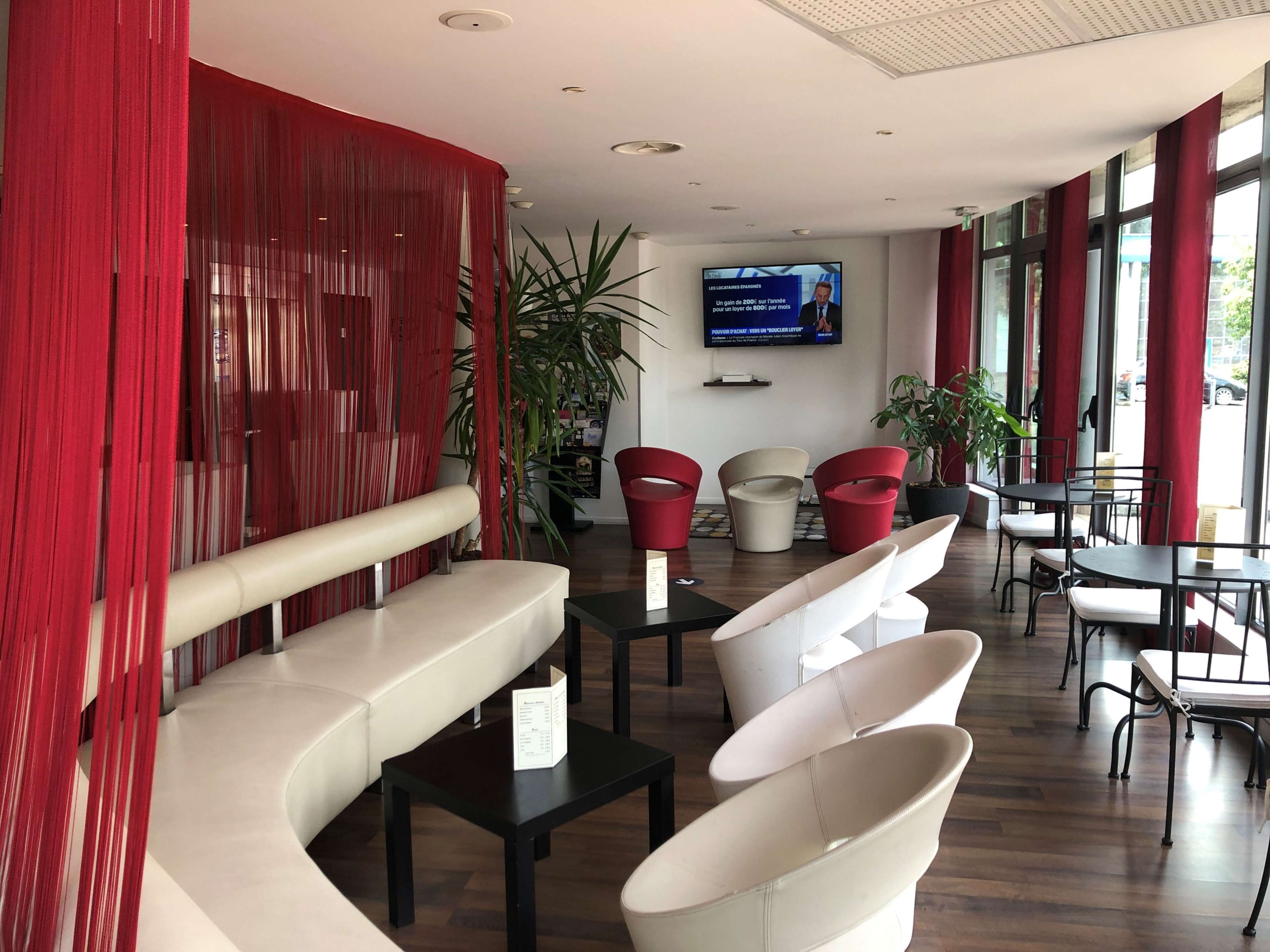 Un interno moderno con zone relax, uno schermo televisivo e piante in vaso.
