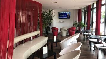 Un interno moderno con zone relax, uno schermo televisivo e piante in vaso.