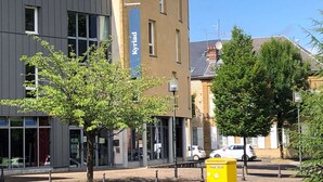 Ein Gebäude mit einem Schild, auf dem „HOTEL KYRIAD“ steht, und einem blauen, vertikalen Schild mit dem Namen „Kyriad“.