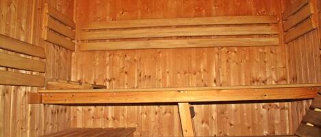 A sauna with wooden benches and a sloped ceiling.
