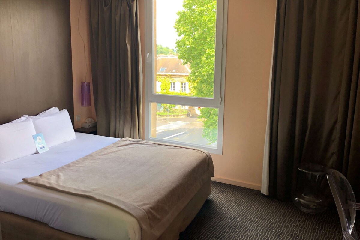 Une chambre d’hôtel avec un lit, une fenêtre et une chaise.