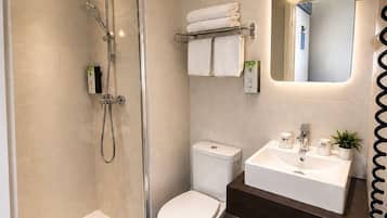 Une salle de bain avec une douche à parois de verre, des toilettes, un lavabo avec un miroir et un porte-serviettes.