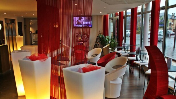 Eine moderne Lobby mit einem roten Vorhang, weißen Sofas und einem Fernsehbildschirm.