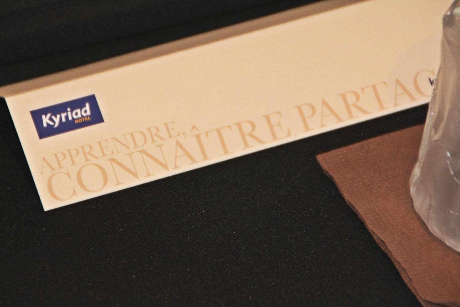 Una caja con el texto "Kyriad Hotel" y "Aprender, conocer, compartir".