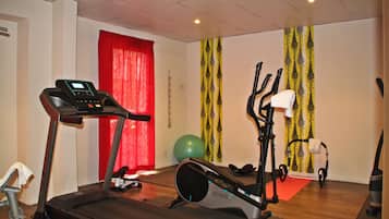 Un gimnasio con cinta de correr, elíptica y pelota de ejercicios.