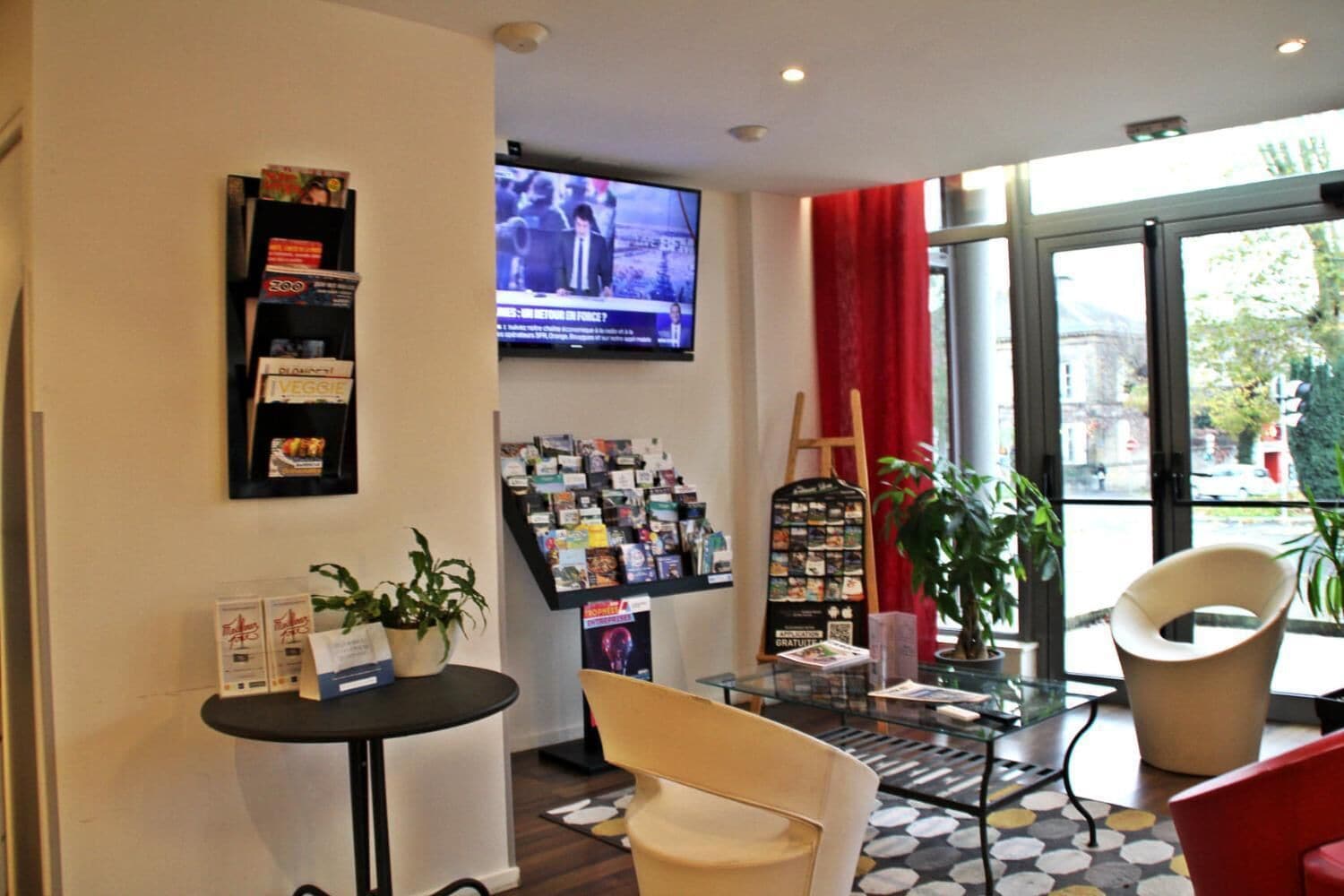 En modern inredning med en receptionsdisk, en tv-skärm, ett glasbord och sittgrupper.