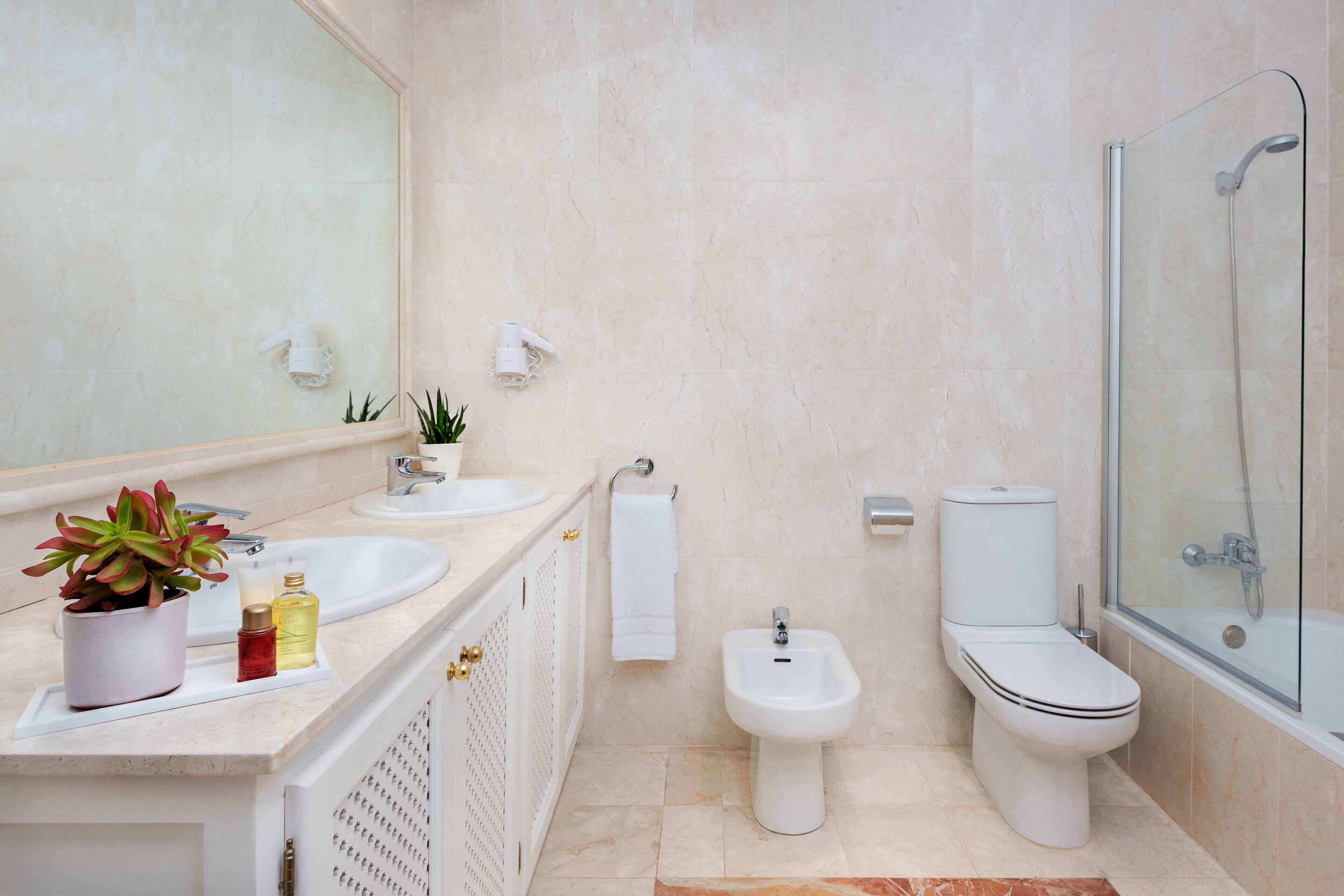 A modern bathroom with a sink, bidet, toilet, and shower.