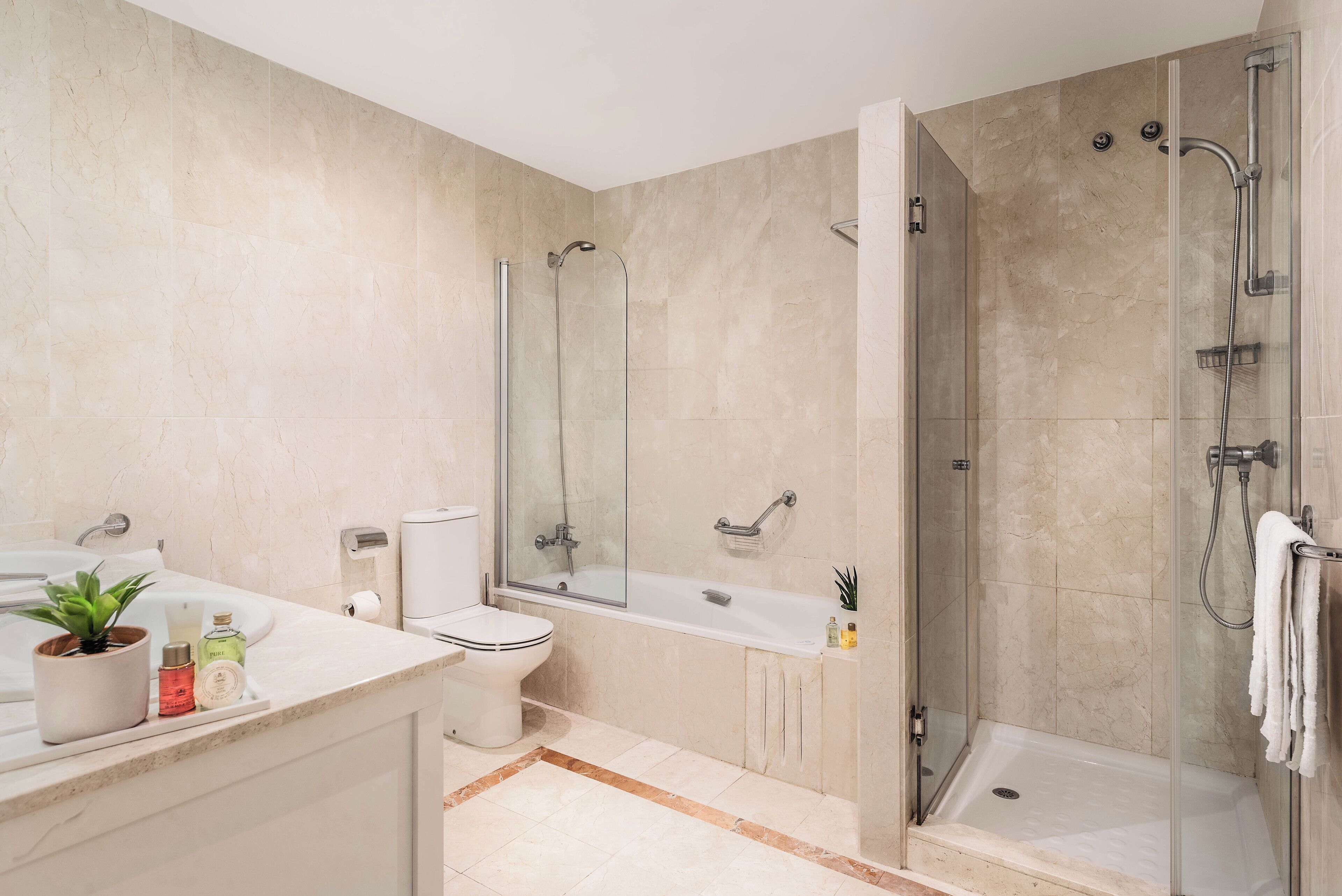 A modern bathroom with a glass-enclosed shower, a bathtub, and a toilet.