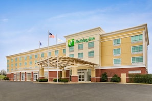 A Holiday Inn hotel with a covered entrance, multiple windows, and a flag. - Holiday Inn Florence by IHG (Florence)