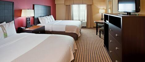A hotel room with two beds, a television, a desk, and a dresser.