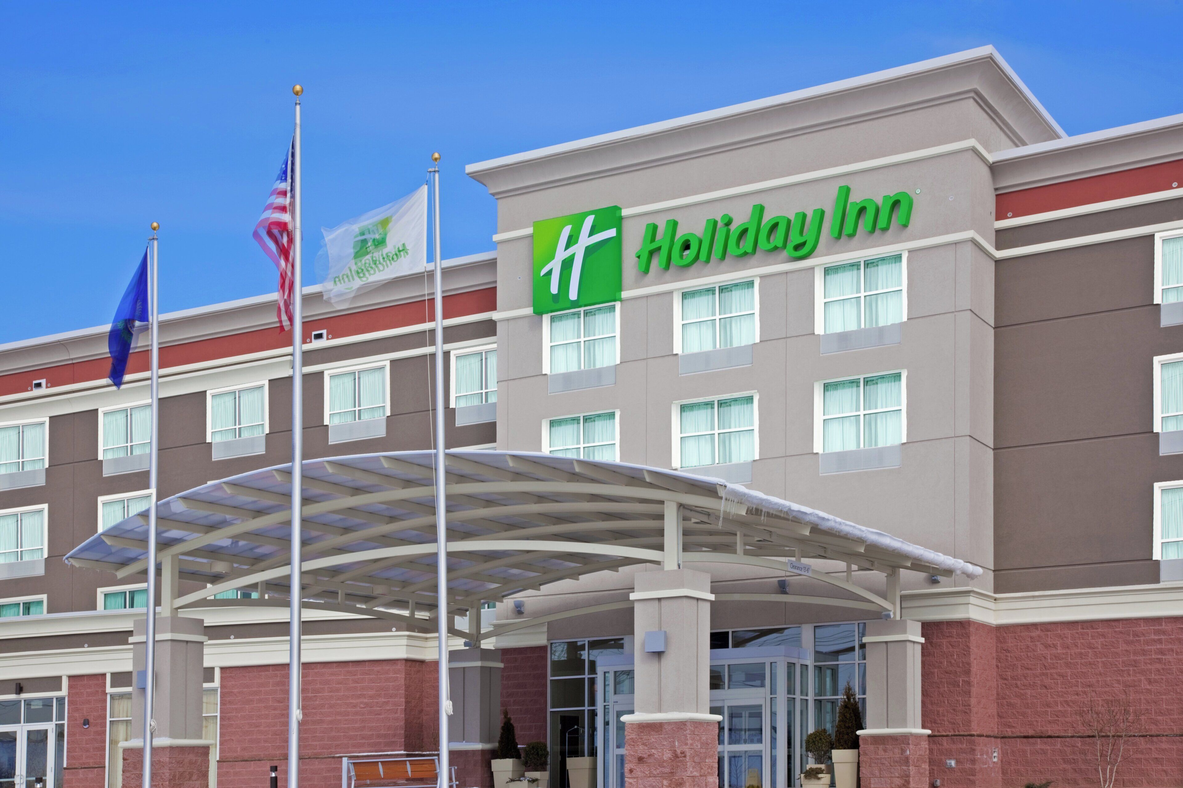 A Holiday Inn hotel with a covered entrance and multiple flags.
