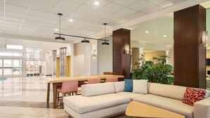 A spacious hotel lobby with a large dining area, a sofa, and a small table. - Holiday Inn Florence by IHG (Florence)