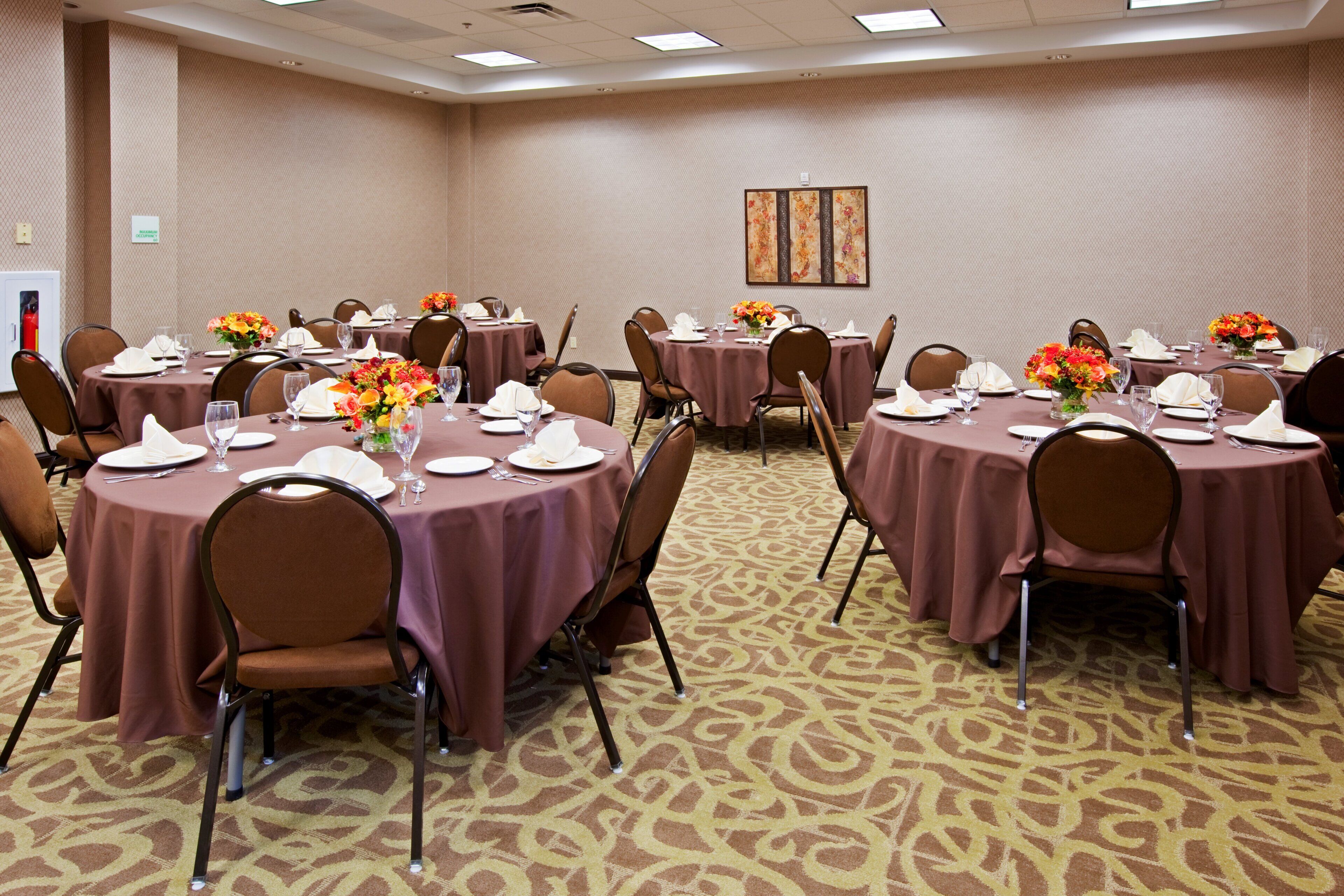A conference room with round tables, chairs, and floral centerpieces.